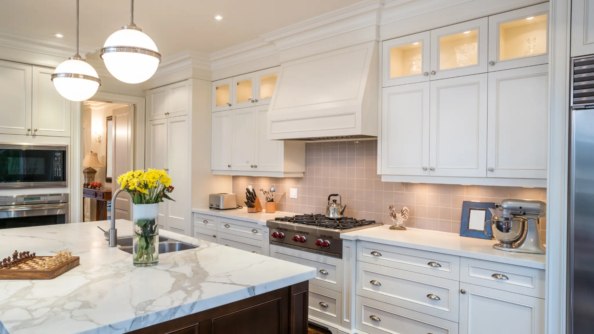 Completed white kitchen with custom cabinetry, stone counters, and a large island