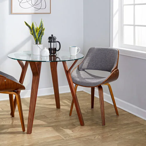 Round glass dining table with walnut legs and curved upholstered chairs