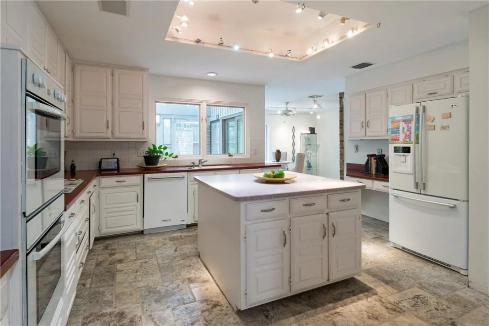 Charleston White kitchen with an island, warm wood-toned counters and glass-door cabinets