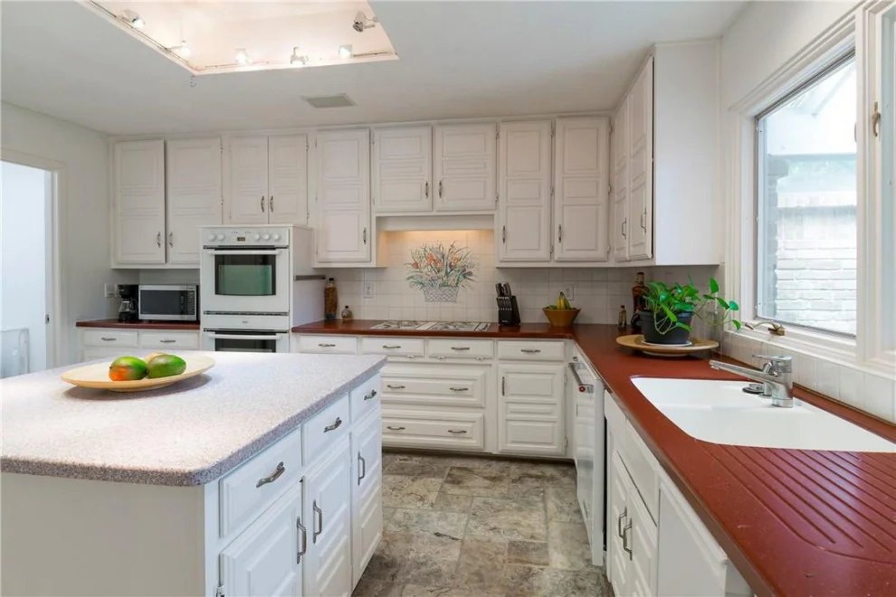 Charleston White kitchen island and perimeter cabinetry with warm wood-toned work surfaces