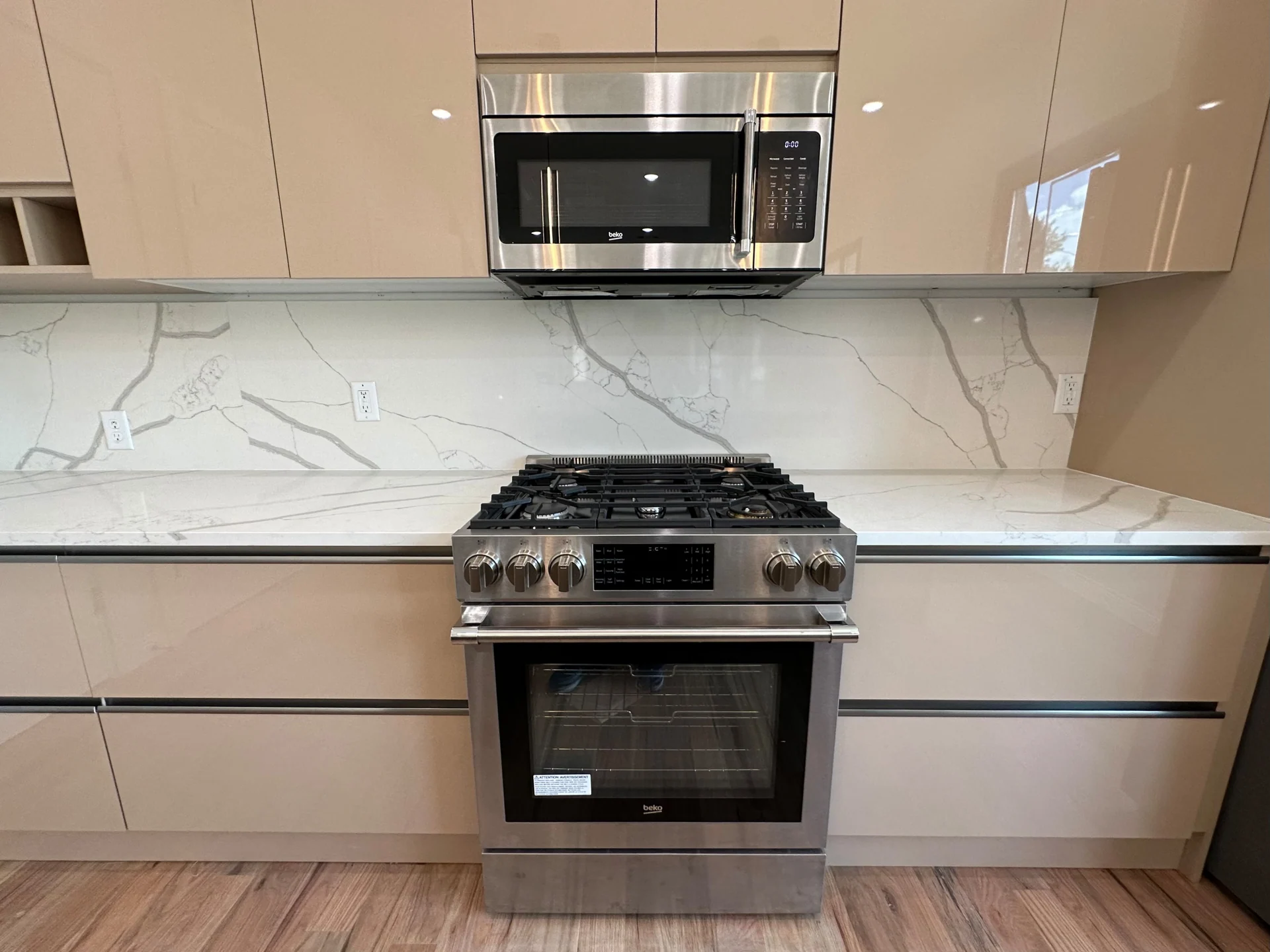 Glossy frameless kitchen cabinetry around a range and veined backsplash