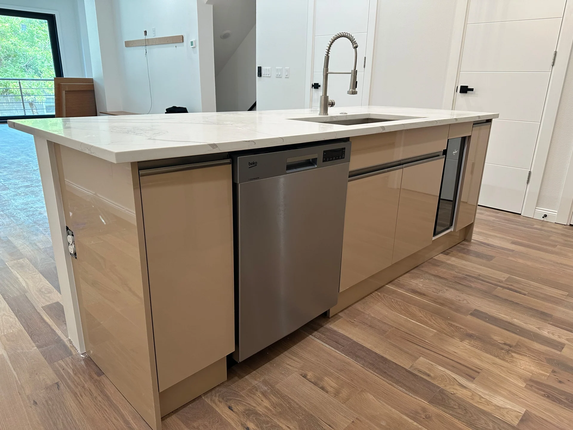 Kitchen island with an integrated sink, dishwasher and warm neutral drawers