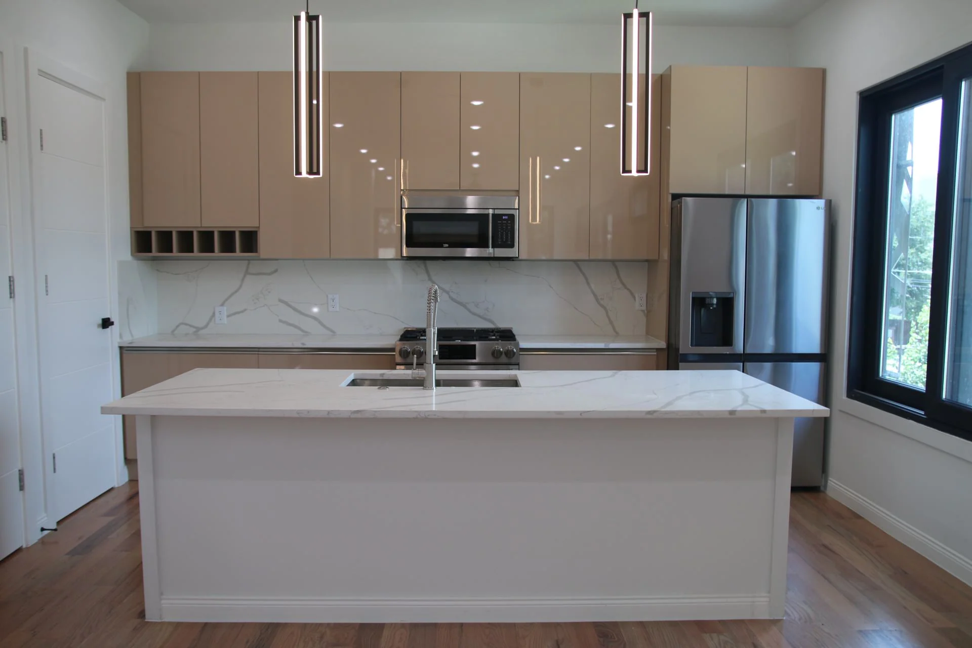 Frameless kitchen with glossy cabinetry, a white island and large windows