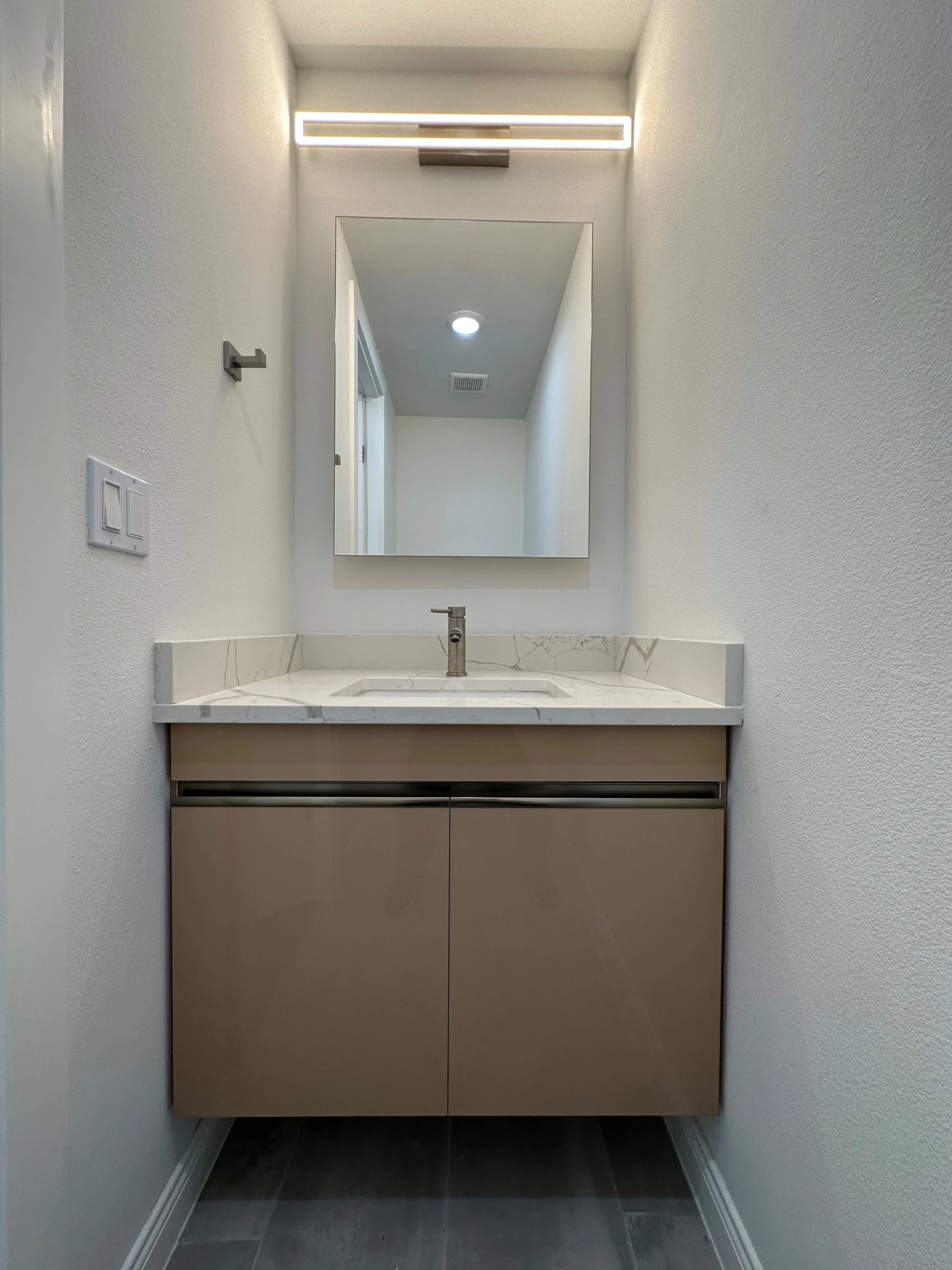 Single warm neutral floating vanity with a wall mirror and bar light