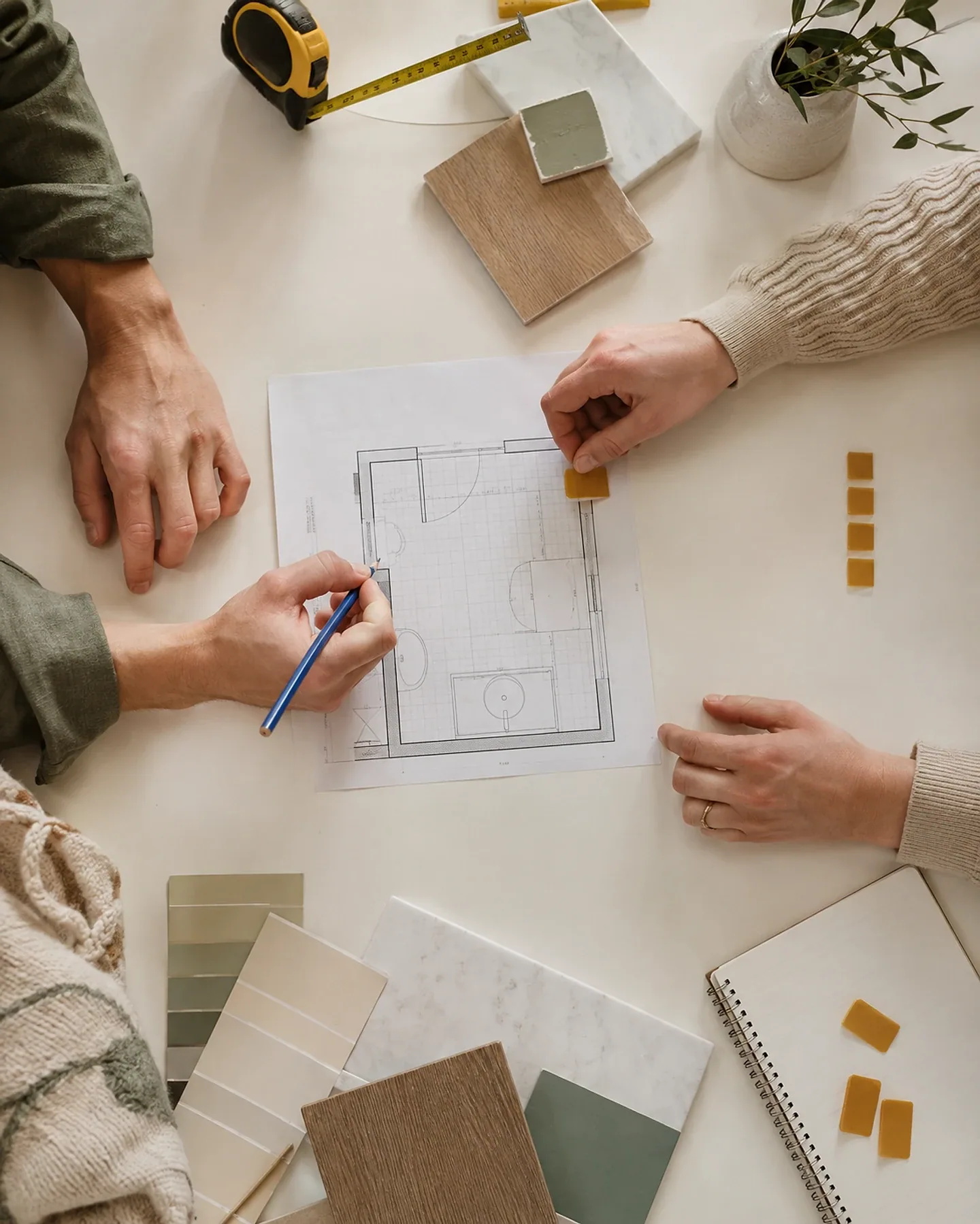Hands reviewing a room plan with a measuring tape and finish samples