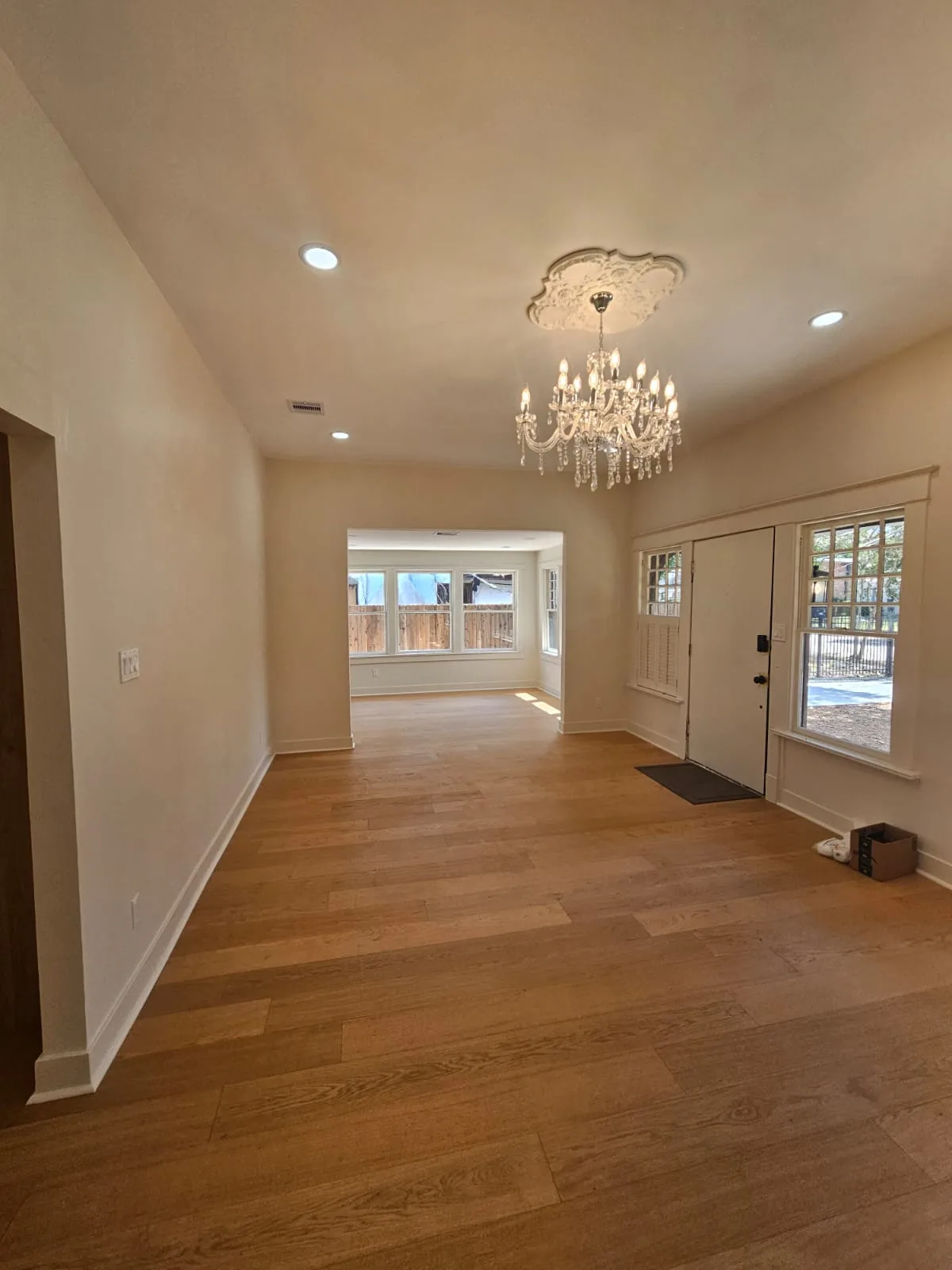 Renovated entry and connected living areas with continuous warm plank flooring