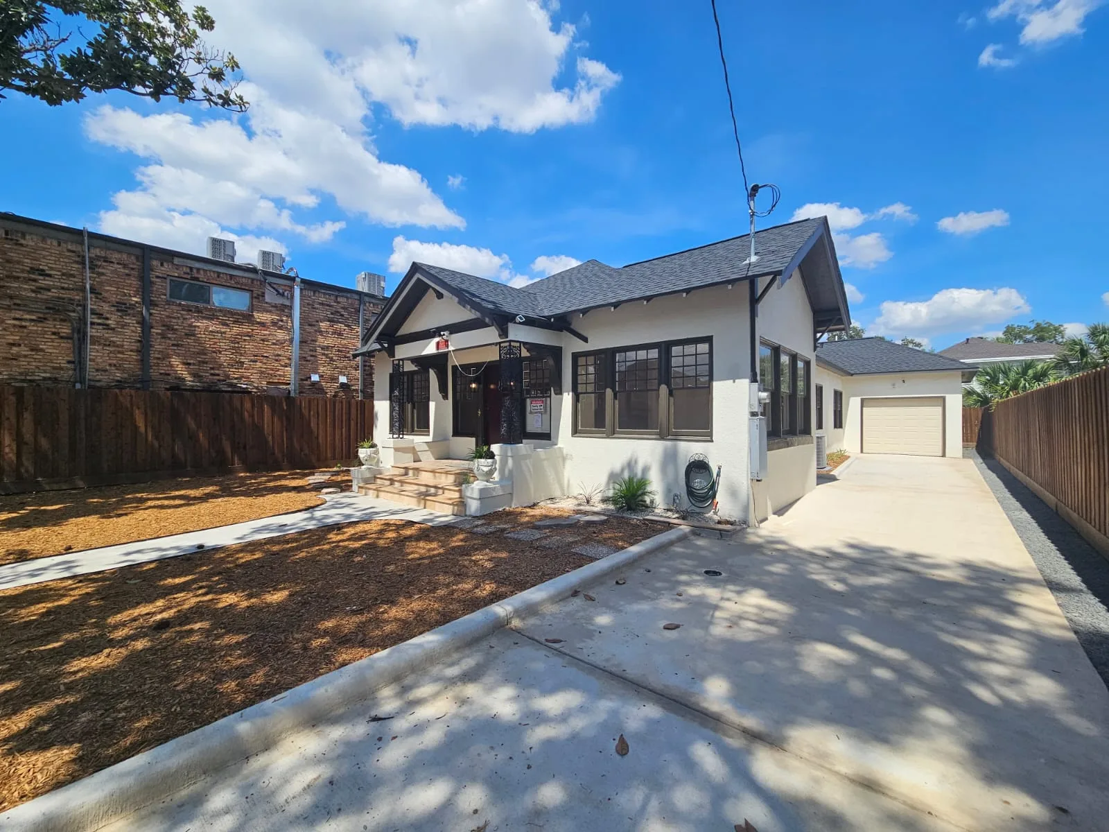 Completed home exterior with light walls, dark window trim and a front porch