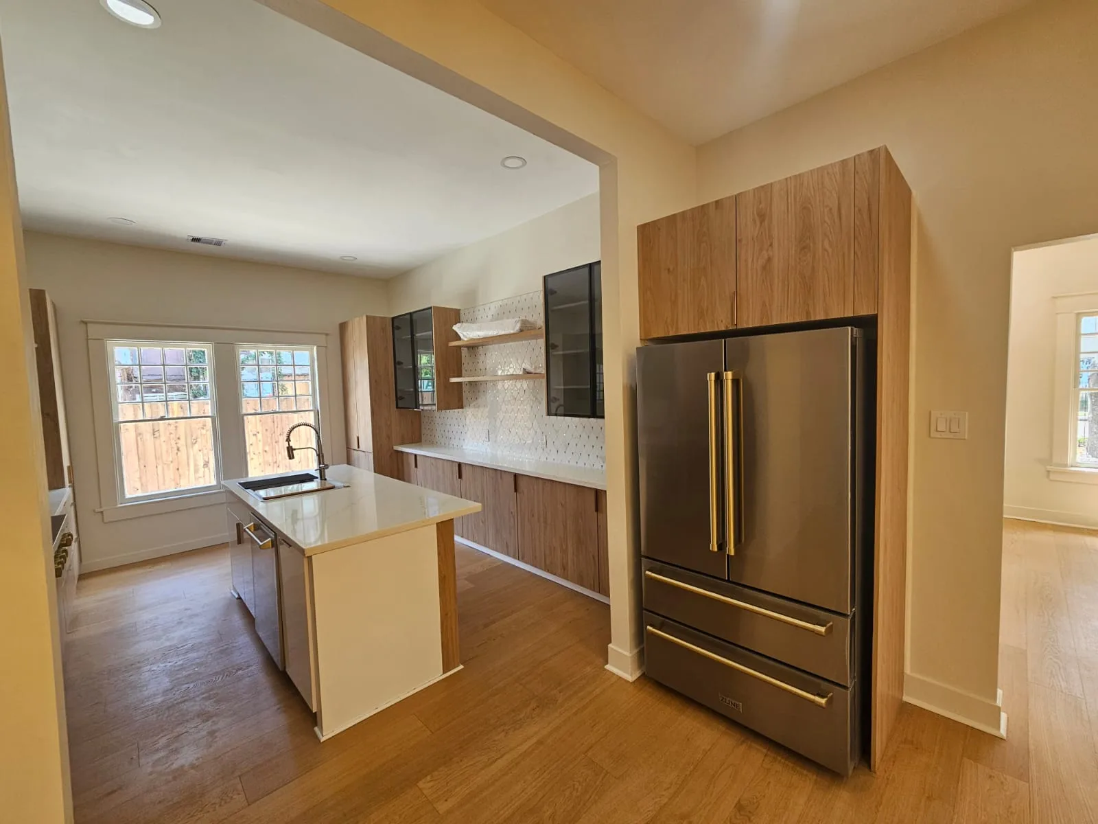 Wood-toned kitchen cabinetry, a white island and glass-front upper cabinets